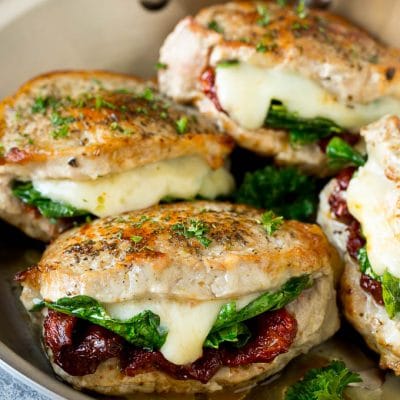 Stuffed pork chops filled with sun dried tomatoes, spinach and cheese in a skillet.