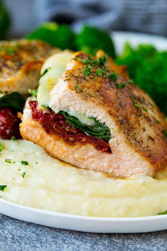 A cross section of a stuffed pork chop served with mashed potatoes and broccoli.