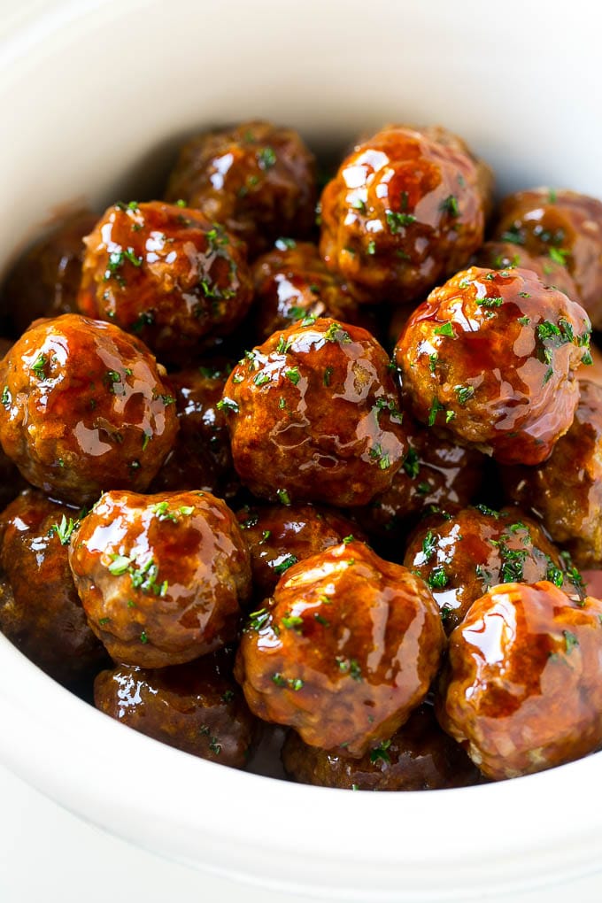 Sweet and sour meatballs garnished with parsley in a slow cooker.