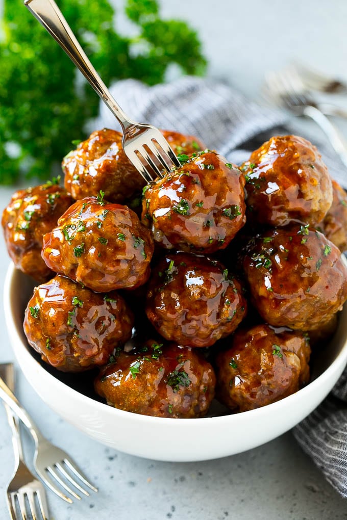 A bowl of sweet and sour meatballs with a cocktail fork in it.