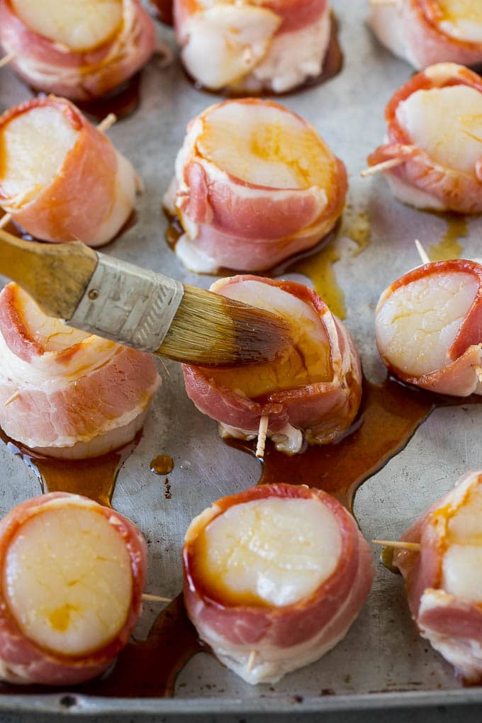 A basting brush coating scallops in maple soy glaze.