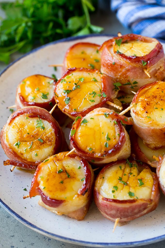 Bacon wrapped scallops coated in glaze and topped with parsley.