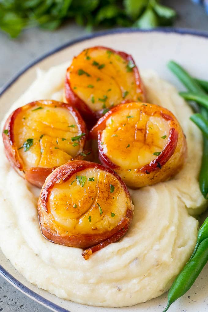 Bacon wrapped scallops served with mashed potatoes and green beans.