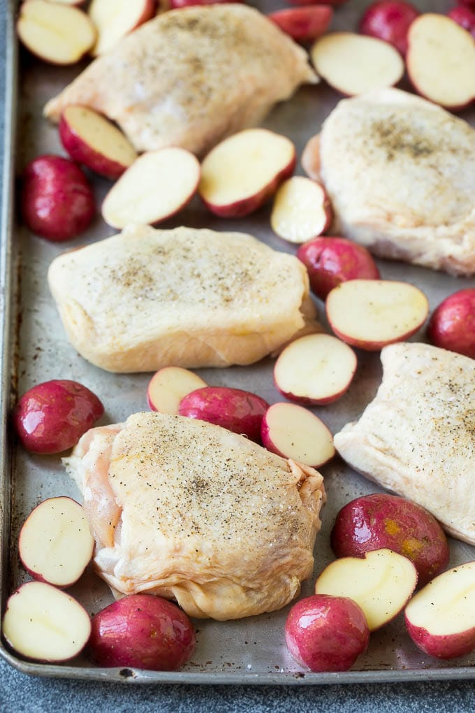 Chicken thighs and halved potatoes on a sheet pan.