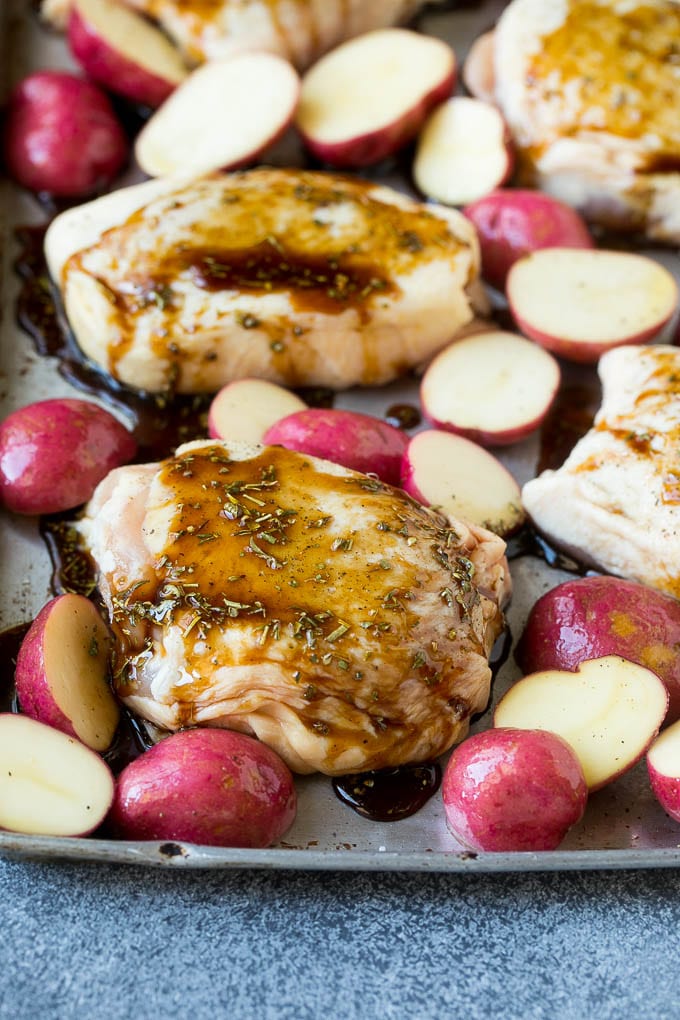 Chicken thighs and potatoes on a sheet pan drizzled with balsamic sauce.