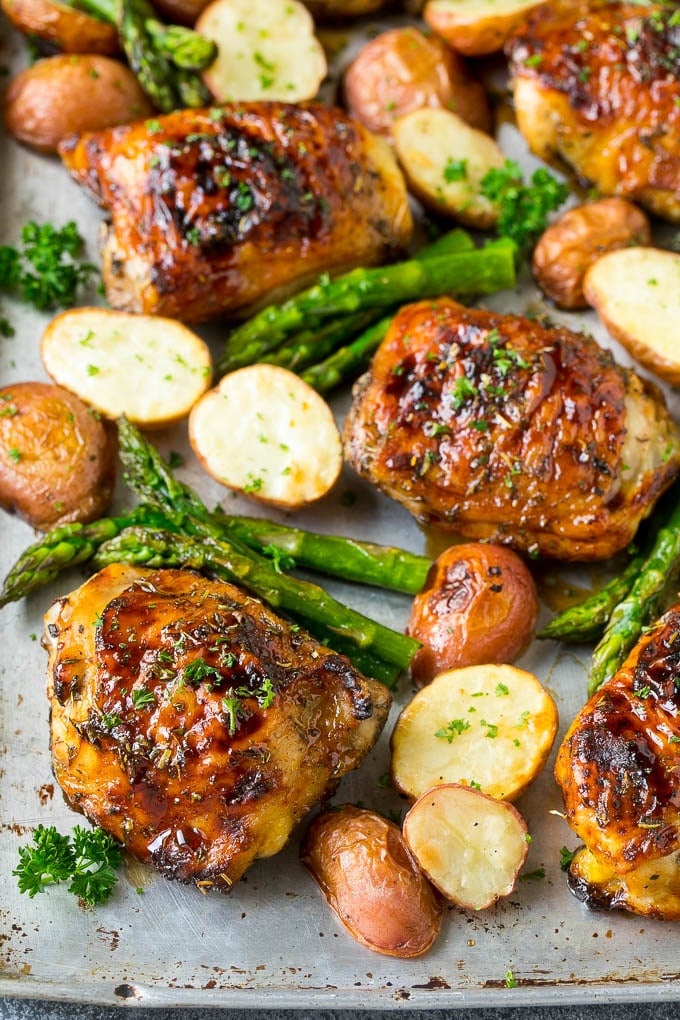 A sheet pan with balsamic chicken, red potatoes and asparagus stalks.