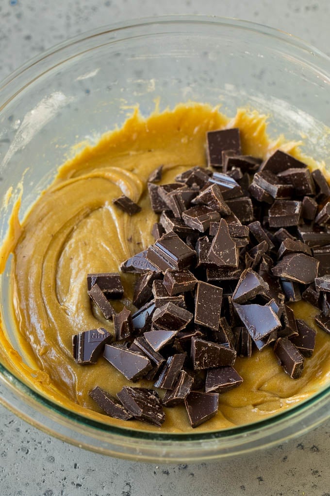 Blondie dough in a mixing bowl with chocolate chunks on top.