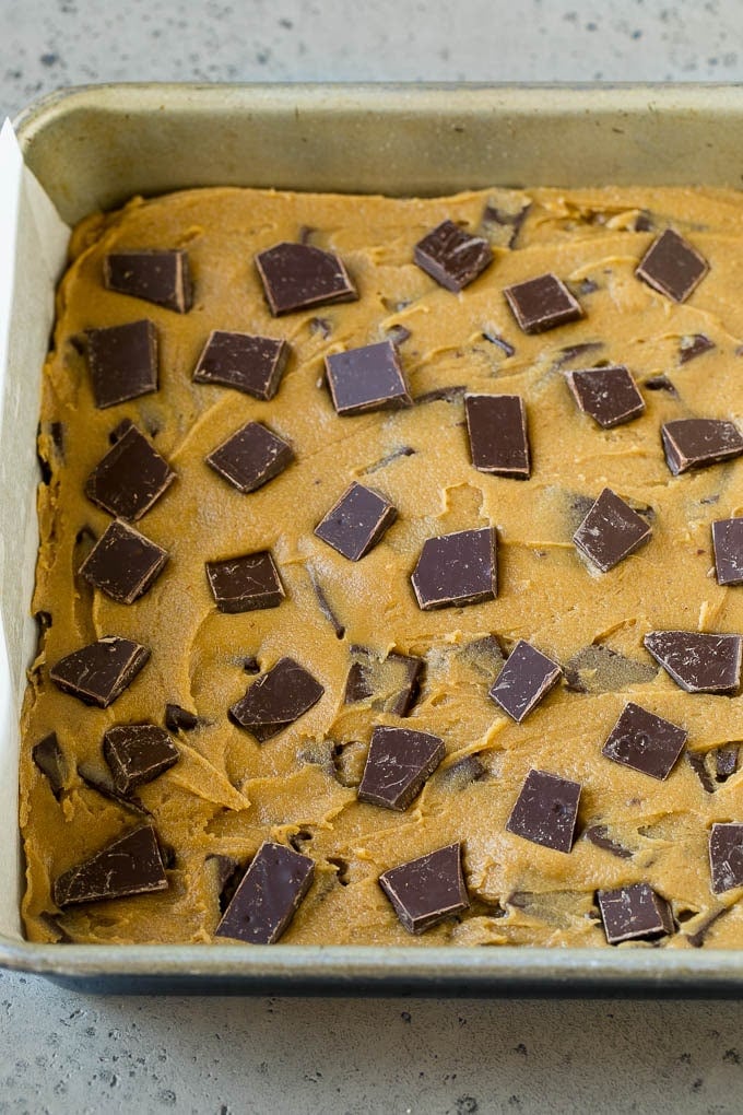 Blondie dough in a baking pan topped with chocolate chunks.