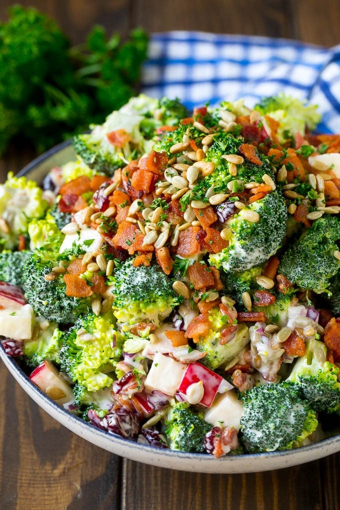 A bowl of broccoli salad made with dried cranberries, apples, bacon and sunflower seeds in a creamy dressing.