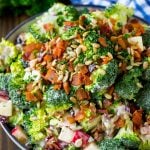 Broccoli salad in a creamy dressing topped with sunflower seeds and bacon.