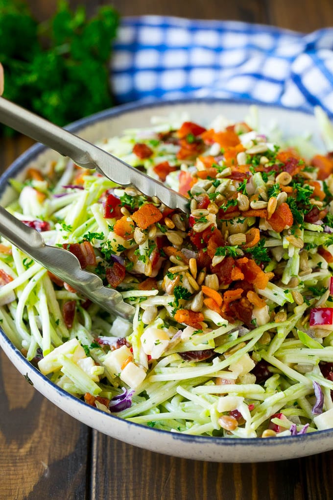 Tongs serving up a portion of broccoli slaw.