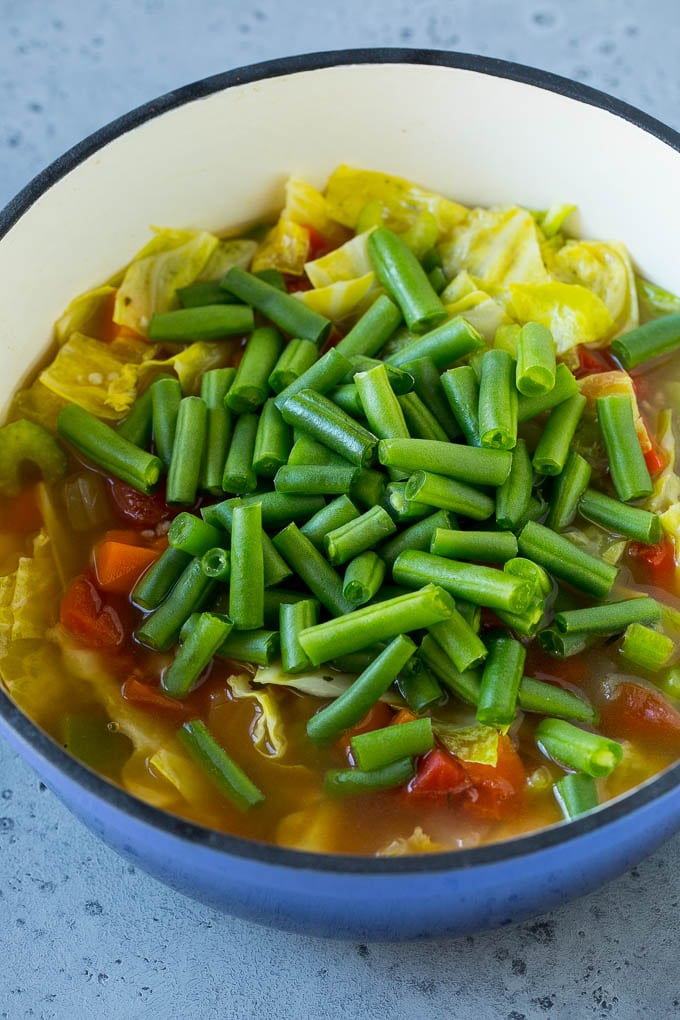 Green beans in a pot of cooked veggies.