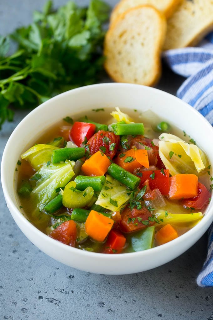 A bowl of cabbage soup with carrots, celery and tomatoes in broth.