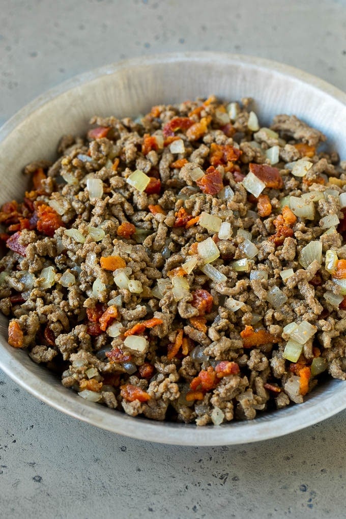 Ground beef, onions and bacon in a pie tin.