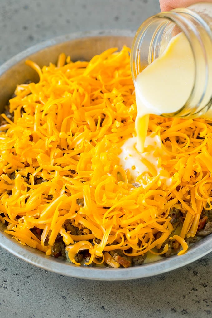 Egg batter being poured over shredded cheese and ground beef.