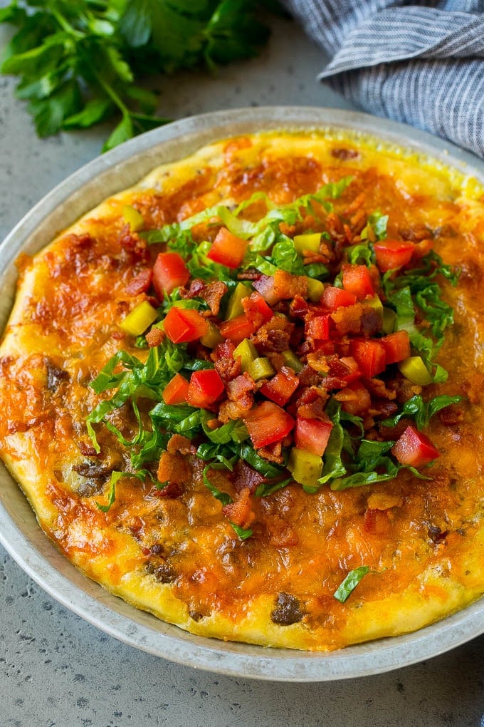 Cheeseburger pie topped with bacon, lettuce, pickles and tomatoes.