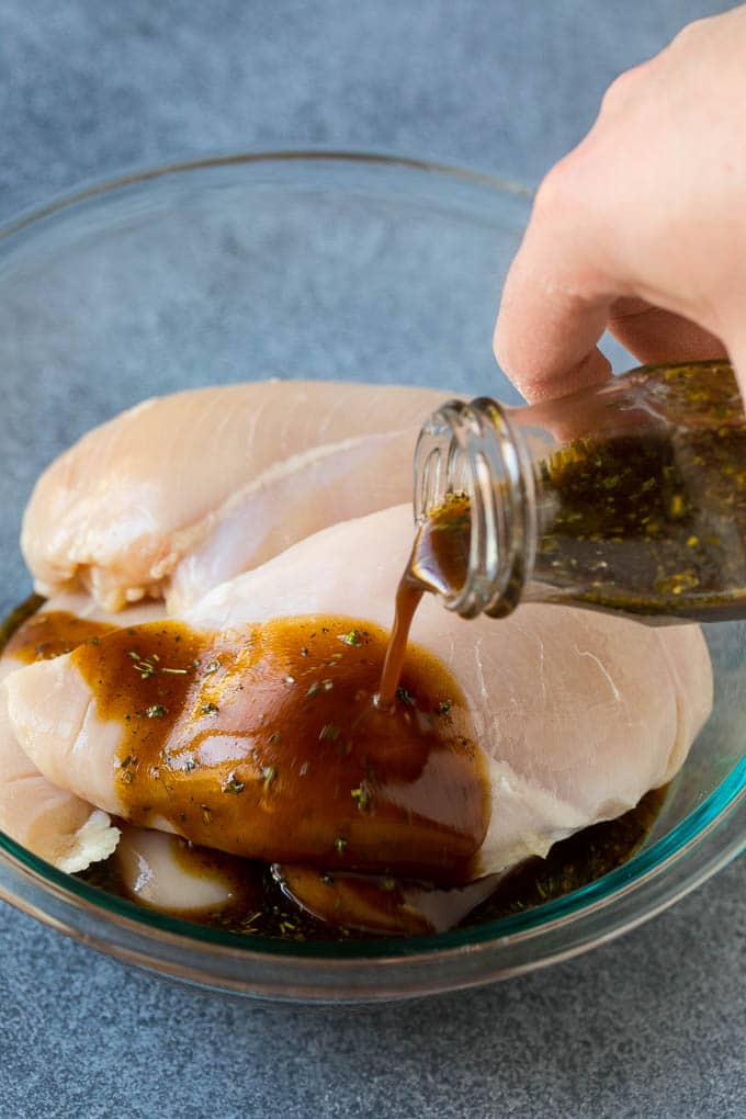 Chicken marinade being poured over skinless chicken breasts.
