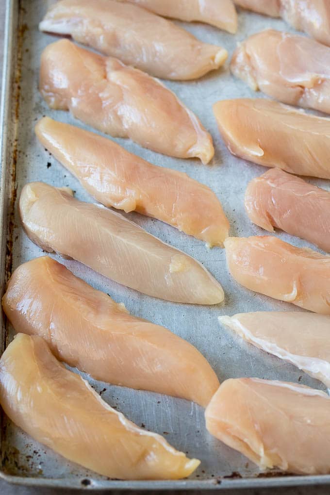 Raw chicken tenders on a sheet pan.