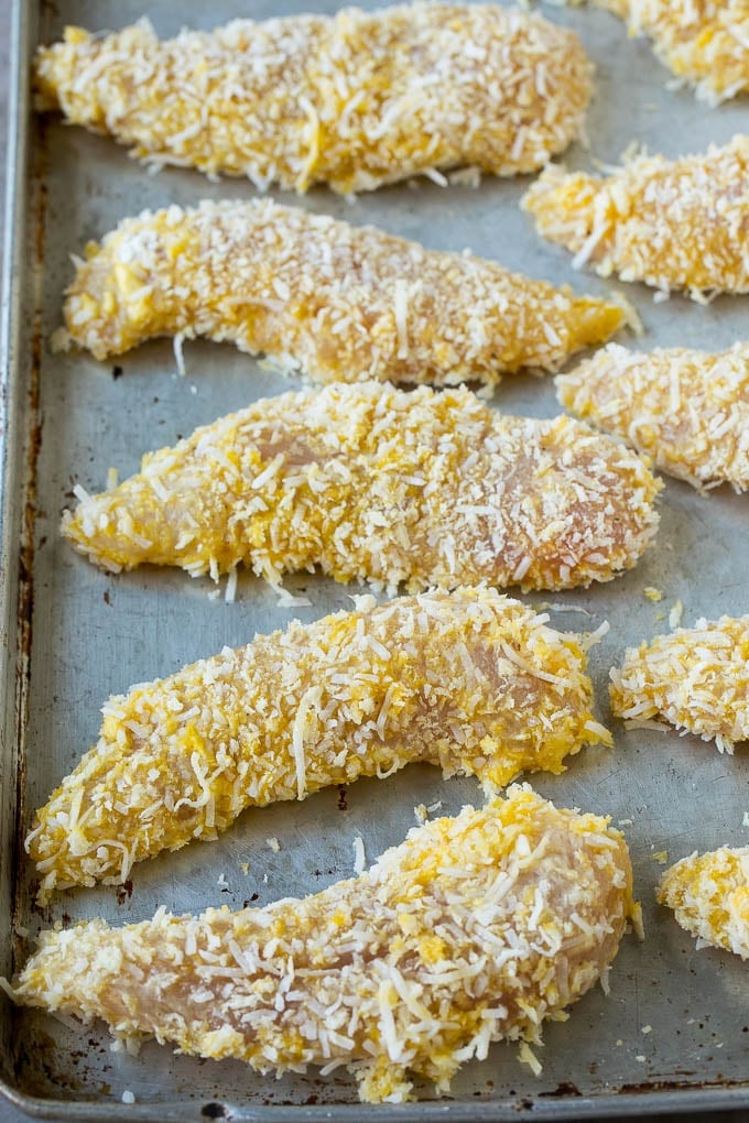 Chicken tenders coated in a coconut mixture on a sheet pan.