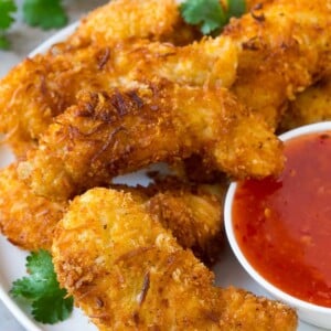 Coconut chicken on a plate served with a side of sweet chili sauce.