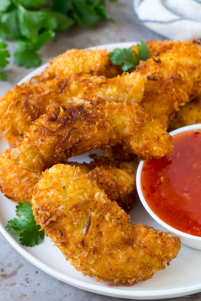 Coconut chicken on a plate served with a side of sweet chili sauce.