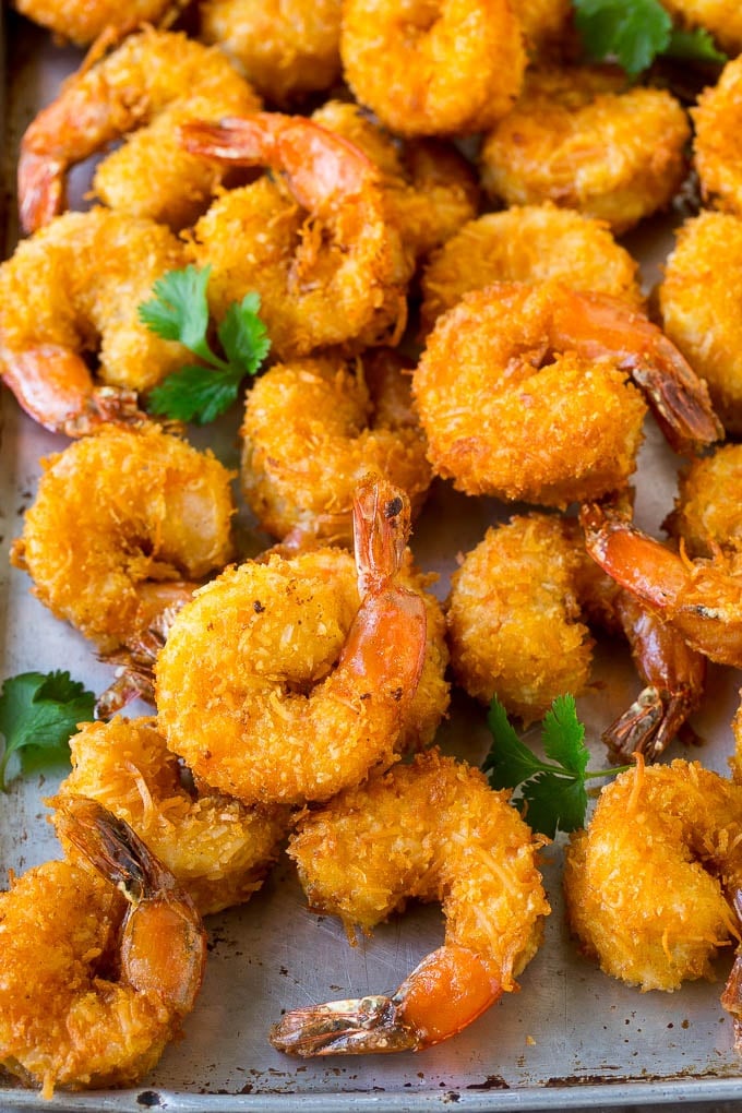 Coconut Shrimp Recipe | Fried Shrimp | Shrimp Appetizer #shrimp #coconut #appetizer #seafood #dinner #dinneratthezoo A pile of crispy coconut shrimp on a sheet pan with cilantro leaves for garnish.