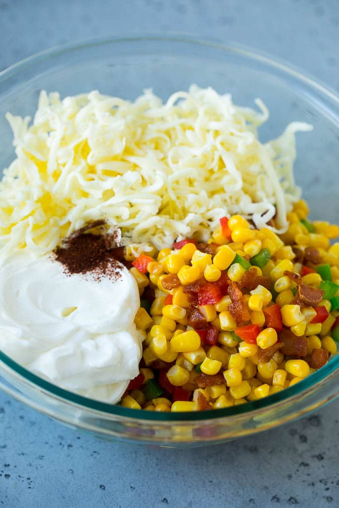 Corn, bacon, bell peppers, sour cream and cheese in a mixing bowl.