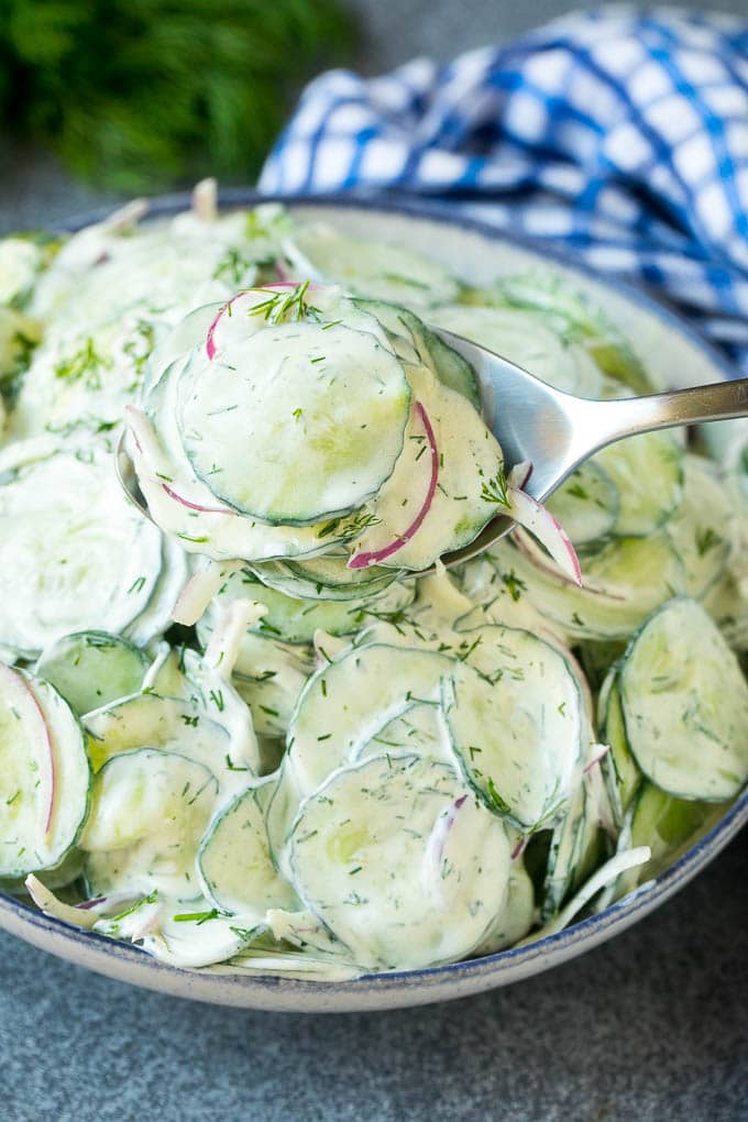 A spoon serving up a portion of creamy cucumber salad.