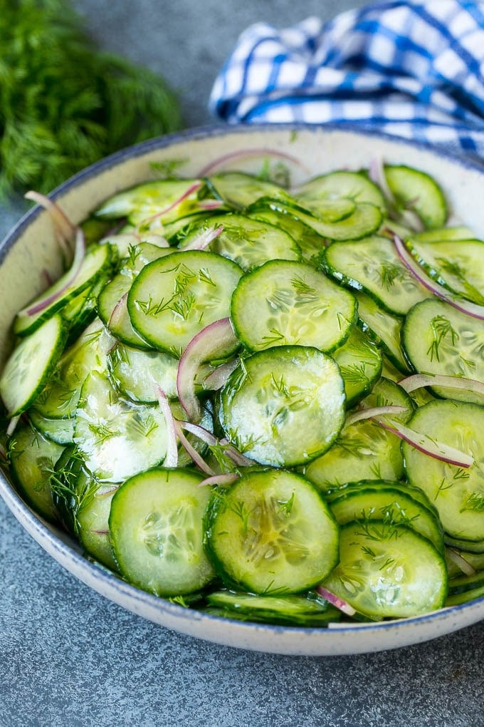 A bowl of cucumber salad made with red onion, thinly sliced cucumbers and chopped dill.