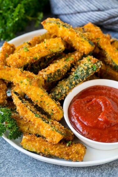 A p late of fried zucchini served with marinara for dipping.