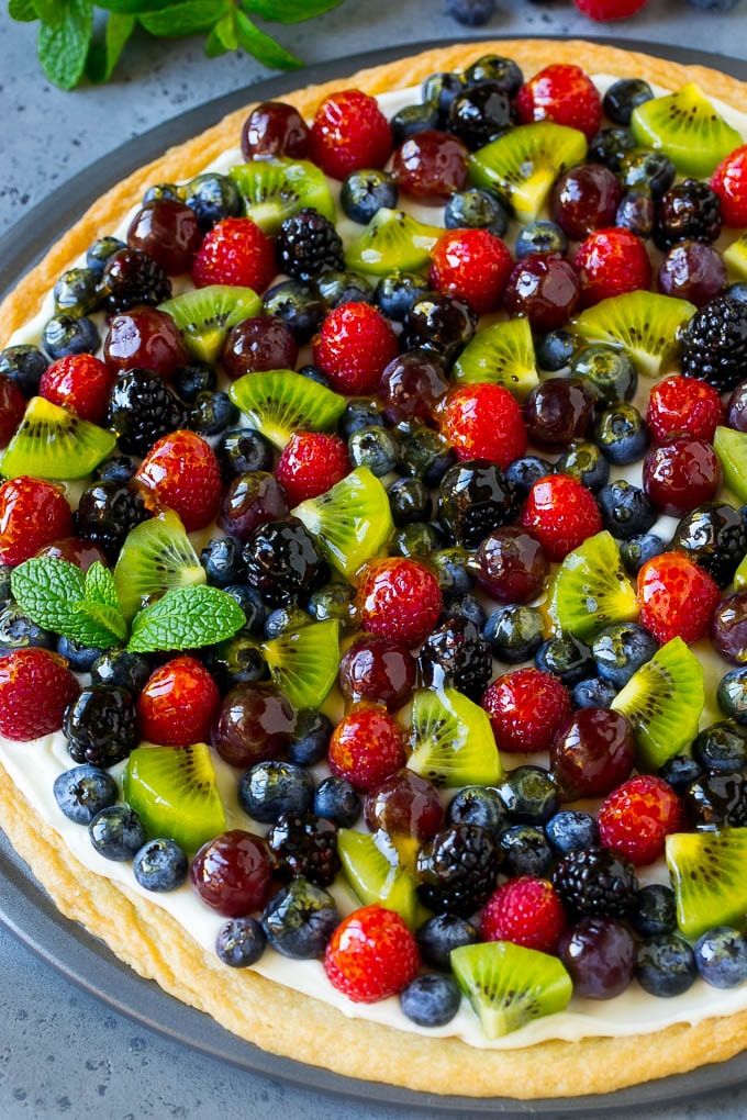 A fruit pizza topped with berries, kiwi and grapes.