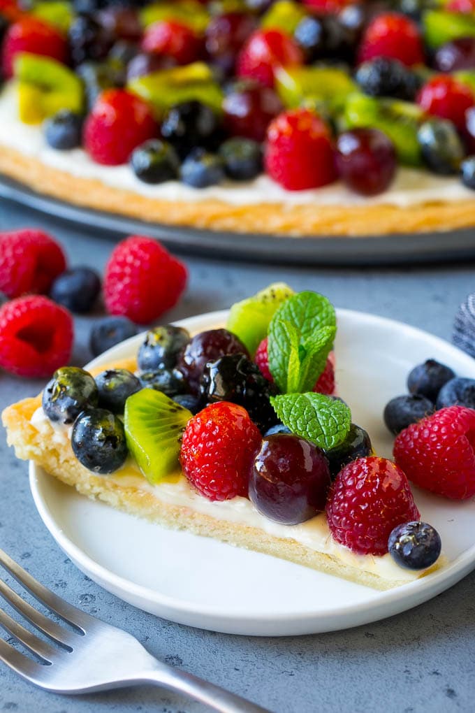 A slice of fruit pizza topped with cream cheese frosting and berries.