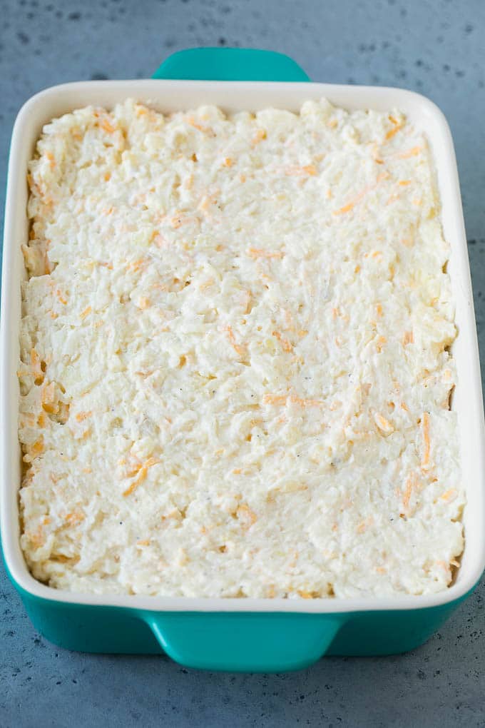 A mixture of hash browns, sour cream, cheese and seasonings in a casserole dish.