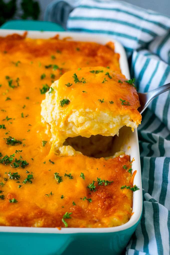 A spatula pulling out a serving of cheesy hash brown casserole.