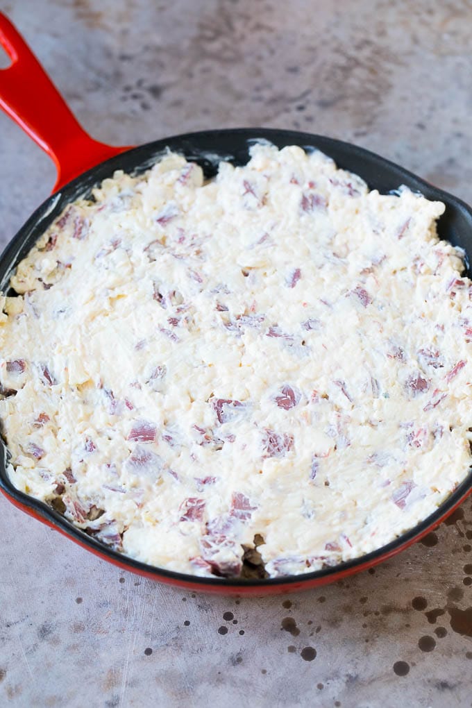 Cream cheese, corned beef and other ingredients spread into a skillet for baking.