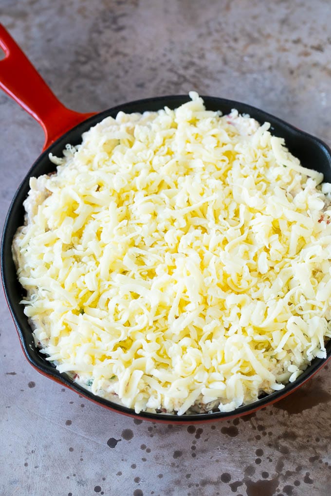A skillet of dip topped with shredded cheese.