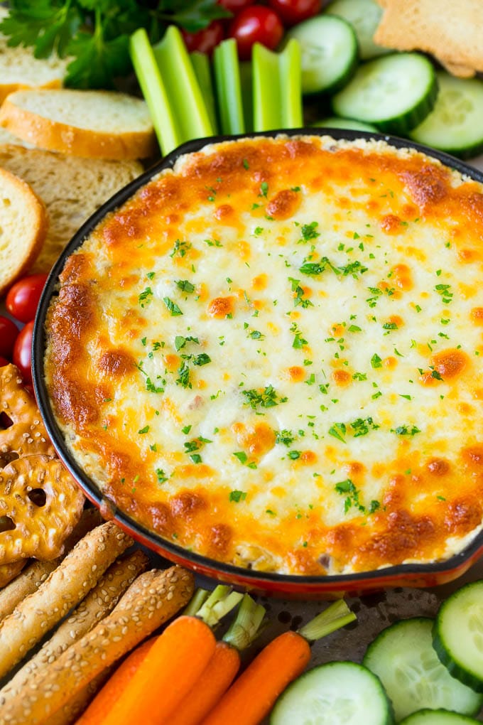 Baked Reuben dip in a skillet served with crackers and vegetables.