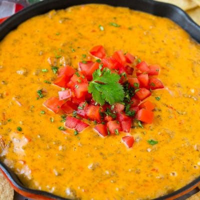 A skillet of Rotel dip topped with fresh tomatoes and cilantro, served with tortilla chips.