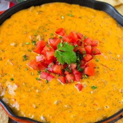 A skillet of Rotel dip topped with fresh tomatoes and cilantro, served with tortilla chips.