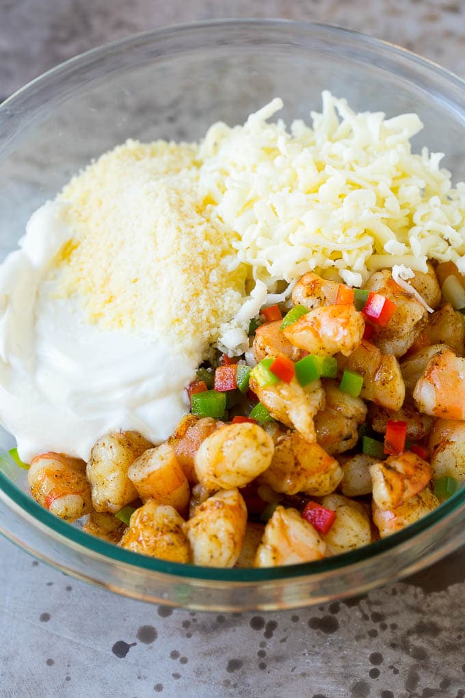 Chopped shrimp, peppers, cheese and sour cream in a bowl.