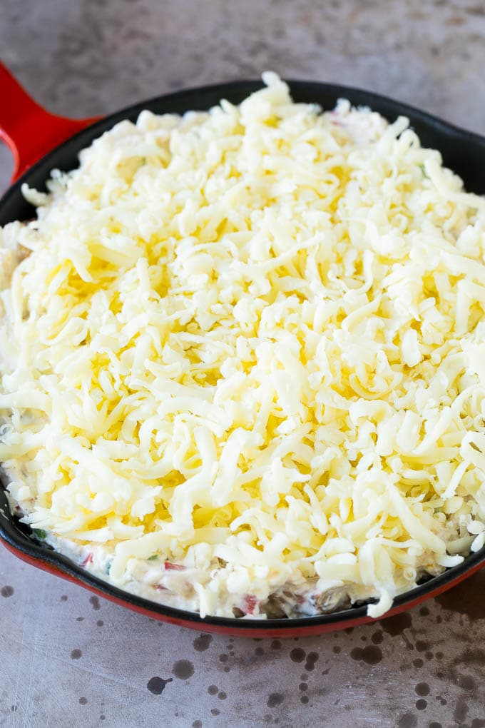 A skillet of shrimp dip topped with a layer of shredded cheese.