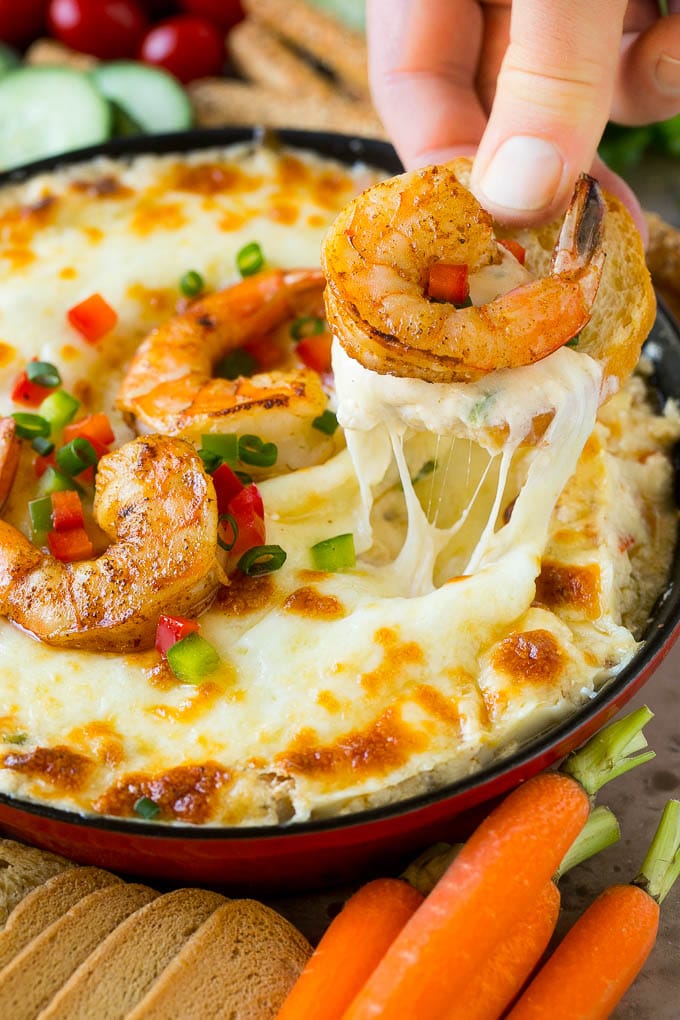 A hand scooping out a portion of shrimp dip with a piece of bread.