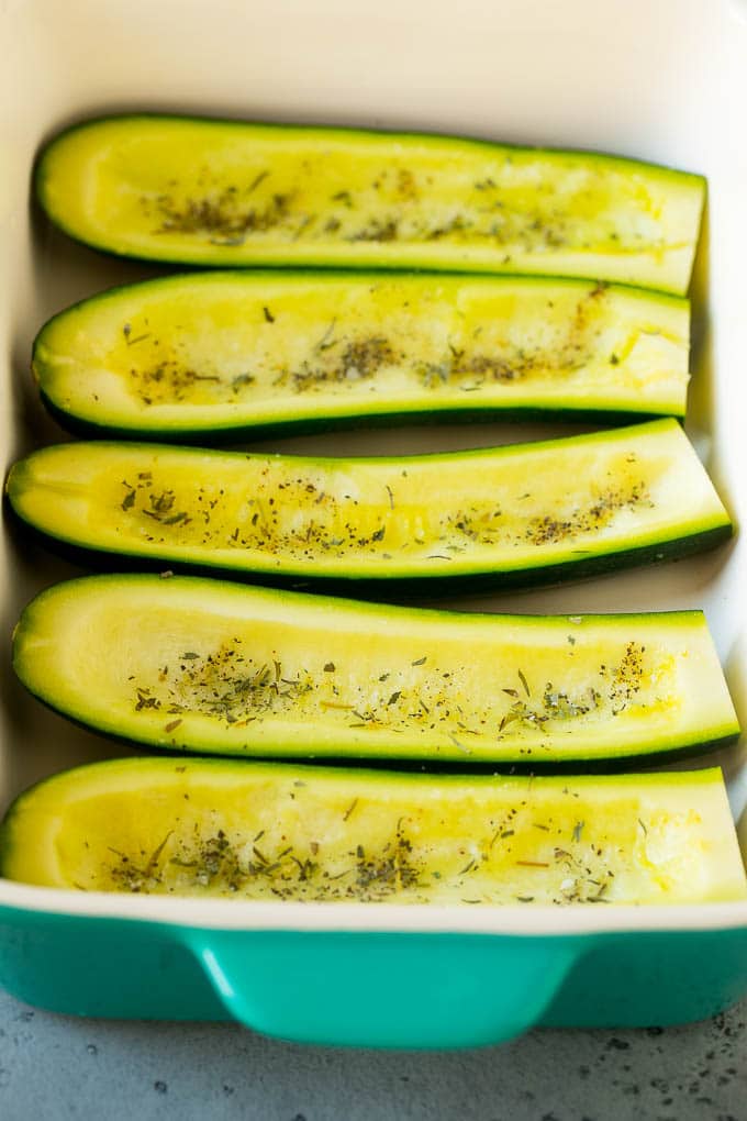 Hollowed out zucchini halves in a baking dish.