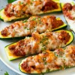 A plate of stuffed zucchini boats filled with a savory meat sauce and topped with mozzarella cheese.