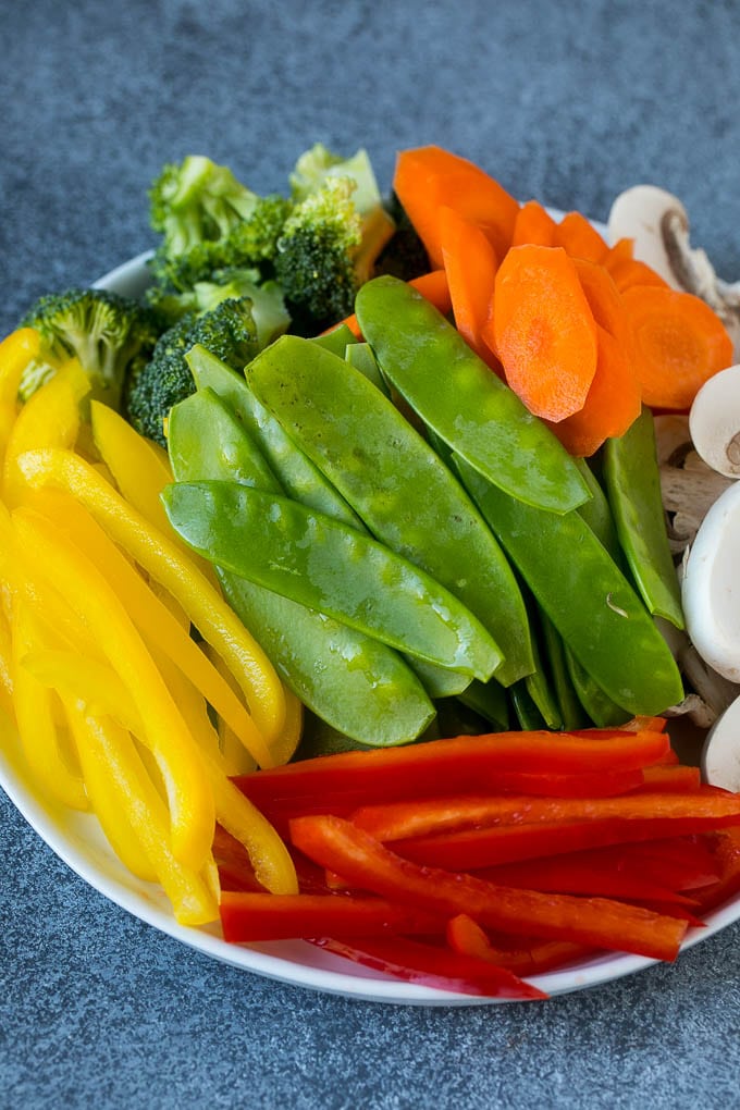 Bell peppers, snow peas, carrots, mushrooms and broccoli on a plate.