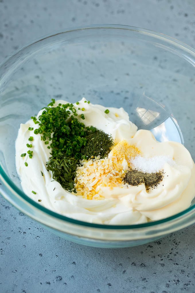 Sour cream, mayonnaise, herbs and spices in a mixing bowl.