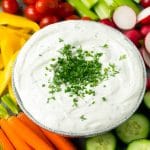 Veggie dip topped with fresh herbs and served with colorful vegetables.