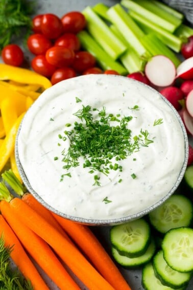 Veggie dip topped with fresh herbs and served with colorful vegetables.