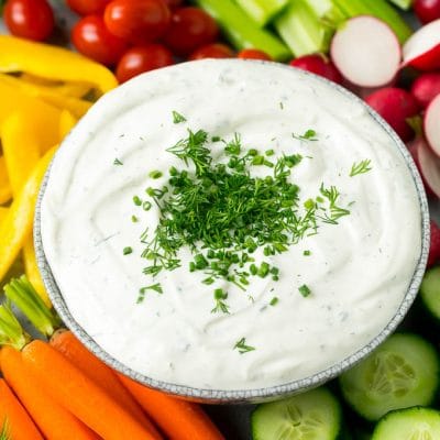Veggie dip topped with fresh herbs and served with colorful vegetables.