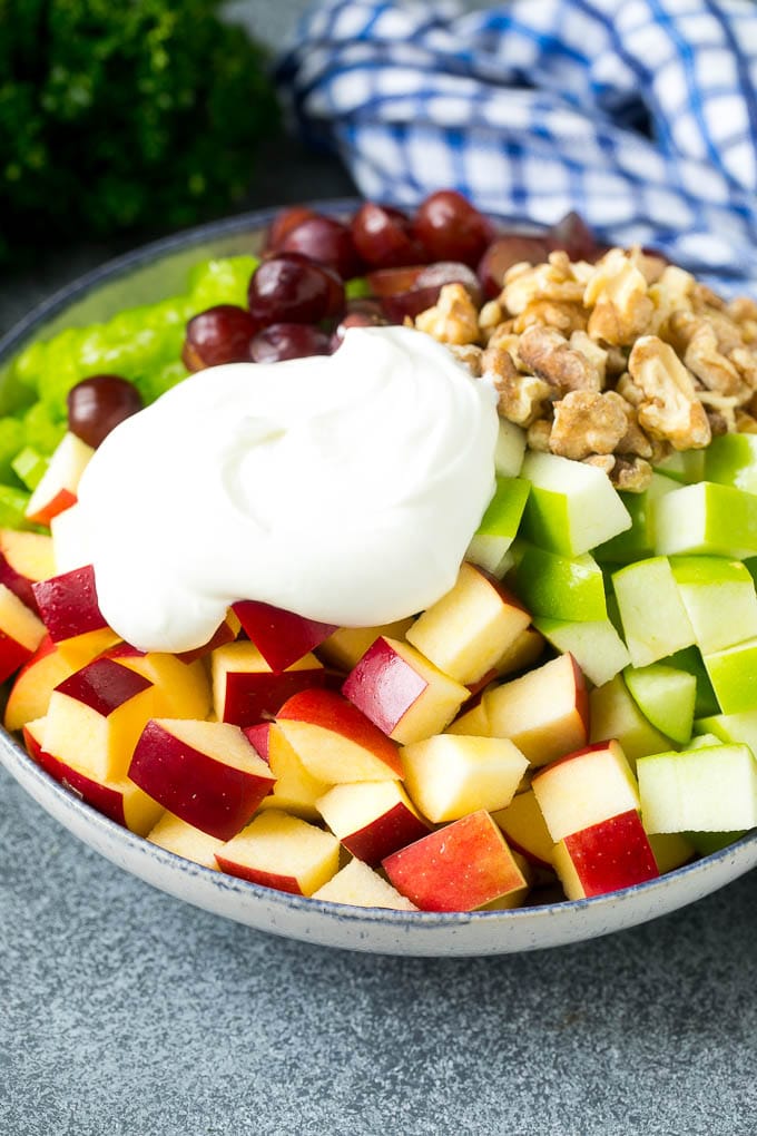 Apples, grapes, walnuts and celery in a bowl topped with creamy dressing.